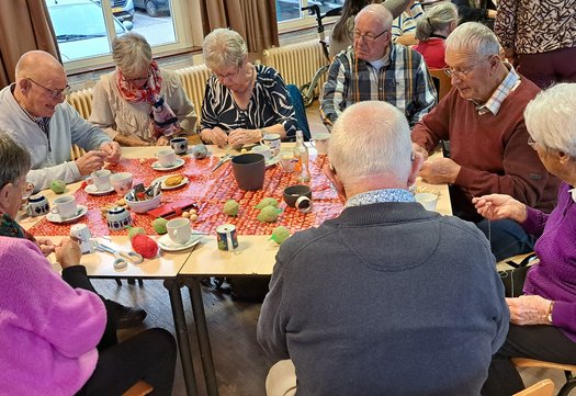 Senioren in gemeenschappelijke ruimte drinken aan tafel